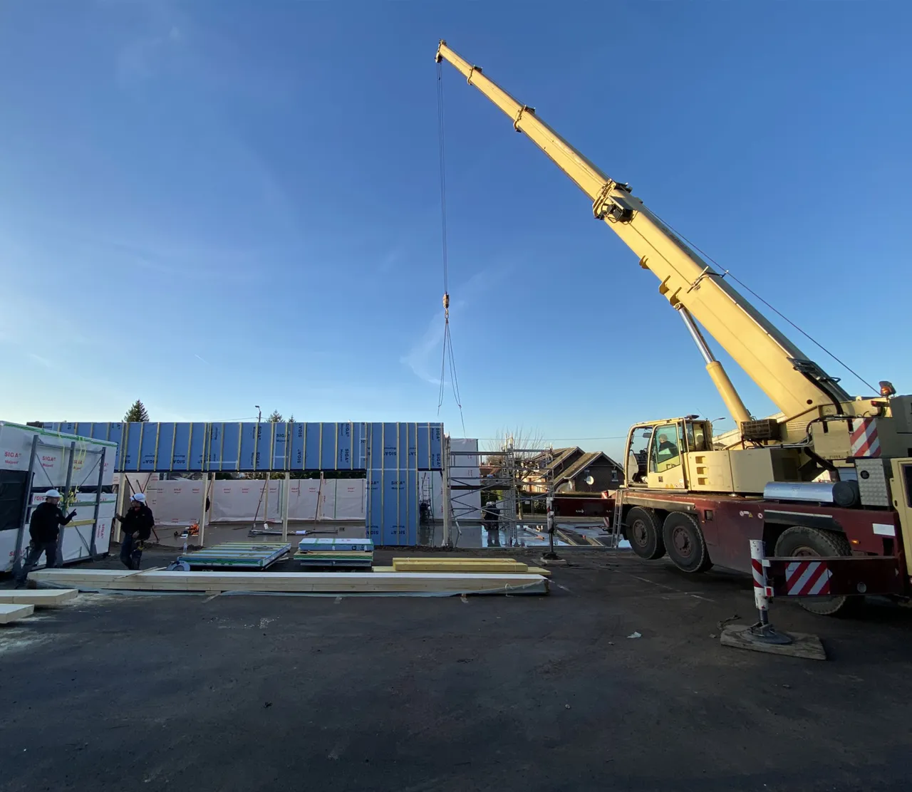 Vue de la grue de chantier qui manœuvre pour installer les éléments de charpente du centre multi-accueil de Sains-en-Gohelle, par les équipes d'Alternative Bois Concept.