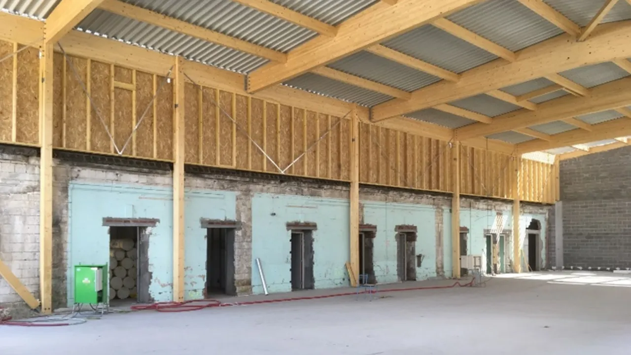 Photographie qui présente l'intérieur de la salle de Bouvigny, en chantier, avec un focus sur la structure portante en bois.