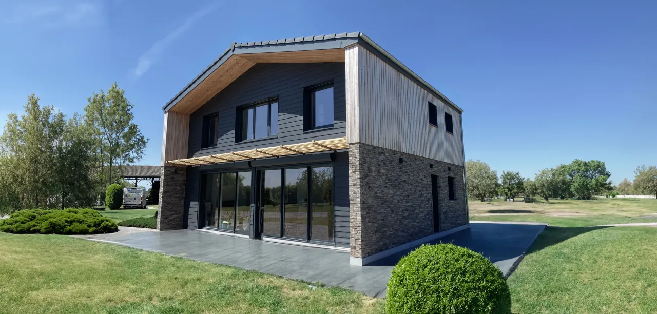 Vue de la façade sud de la maison individuelle de Rexpoëde, une maison à ossature bois réalisée par Alternative Bois Concept